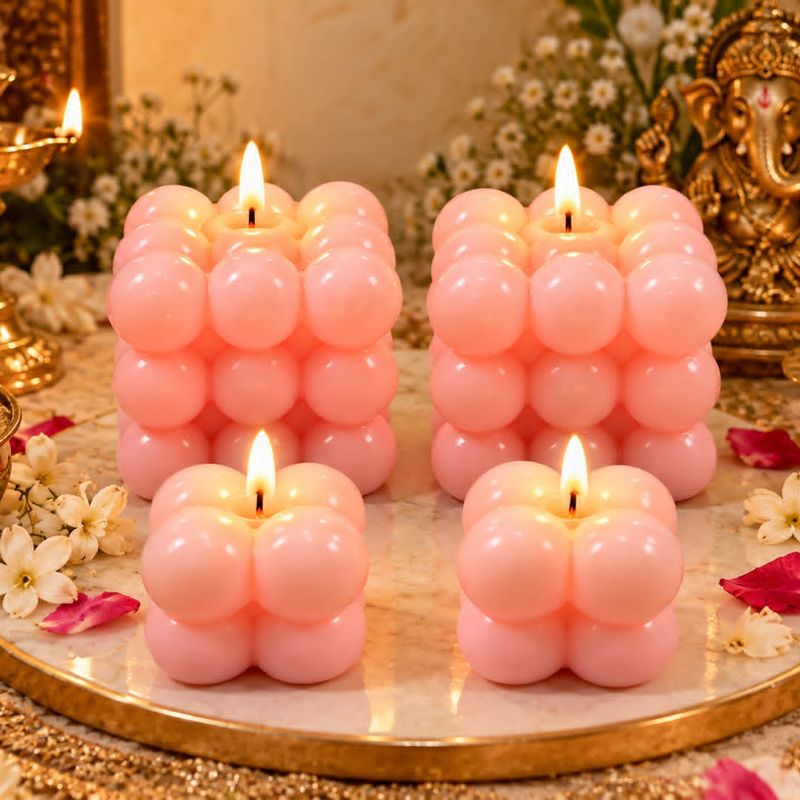 Four pink bubble cube candles on a marble platter beside a Ganesha idol