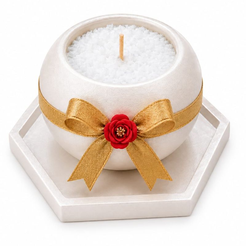 White sphere candle tied with a gold bow on a hexagon tray