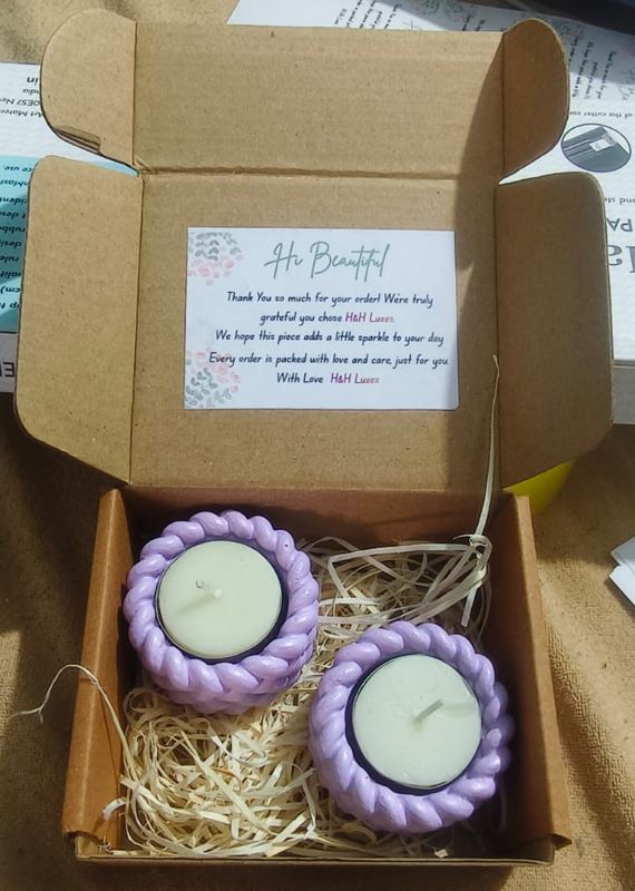 Two lilac braided tealight holders packed in a kraft box with a thank-you card from H&H Luxes