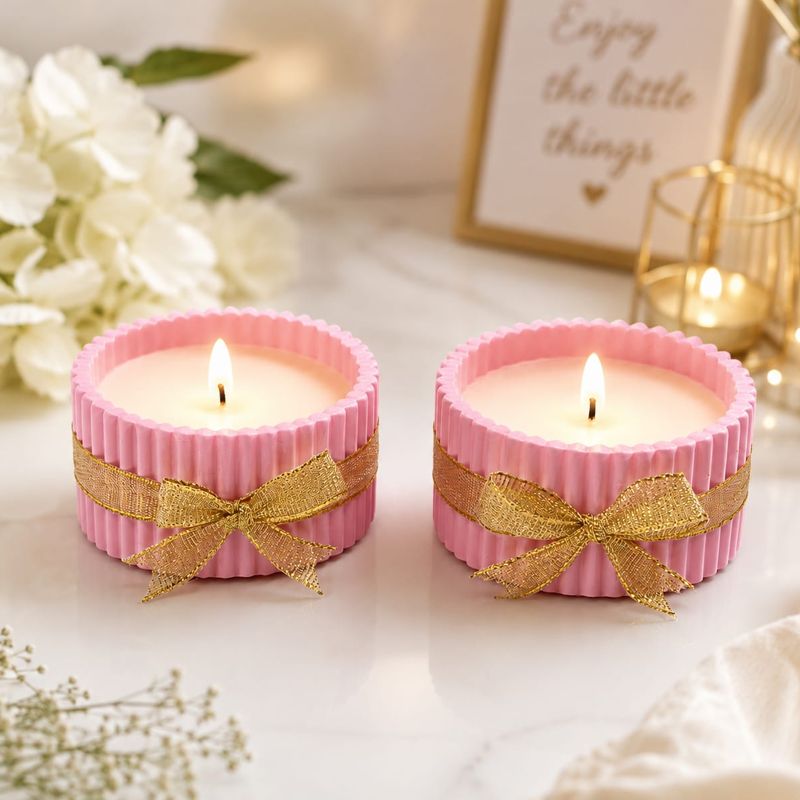 Two pink ribbed candles tied with gold ribbon bows
