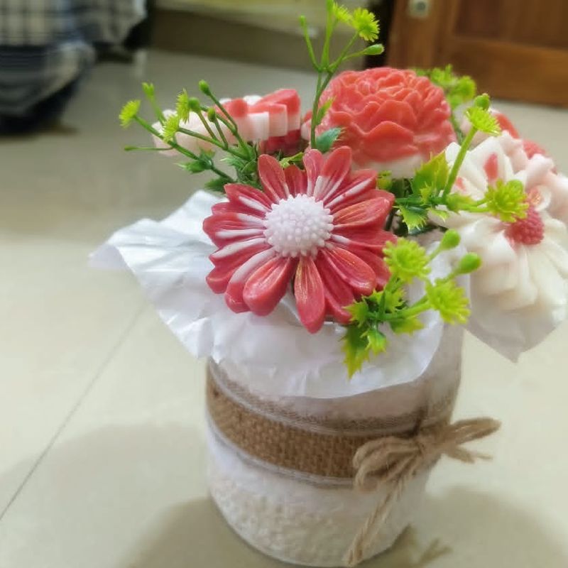 Pot of handmade wax flowers in coral and white, wrapped in burlap and twine